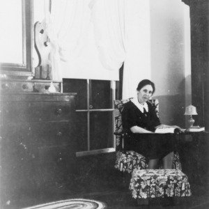 Woman sitting in chair reading at home