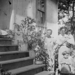 Women and children in front of brightly painted and flower decorated home