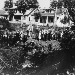 Group of women standing in a garden in front of a row of houses
