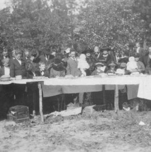 Exterior view of people standing at long table in Columbus County, 1920