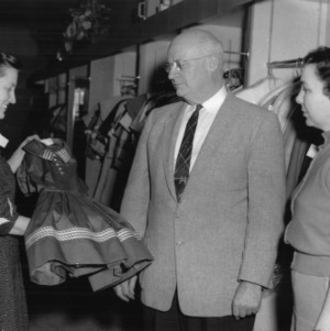 Two women and one man standing in front of racks of clothing