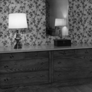 Interior view of dressers placed against a wallpapered wall