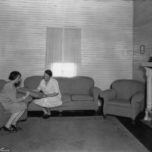 Mrs. Joe Kelly and agent inspecting upholstering job in living room, Southeastern District, 1925-1930