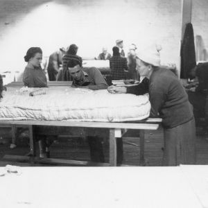 Three women and a man sewing a mattress in Stanly County