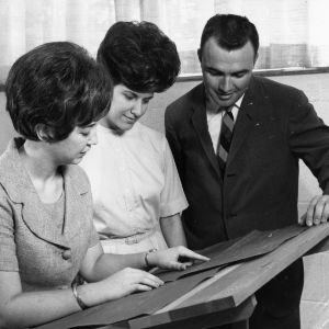 Home economics extension service worker looking at blueprints with man and woman, May 24, 1967