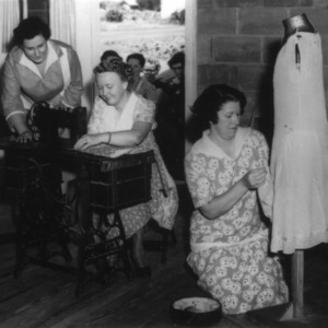Three women preparing a demonstration with four women standing behind them in a doorway