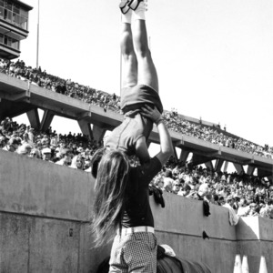 Two North Carolina State University cheerleaders performing on the sidelines during a football game.