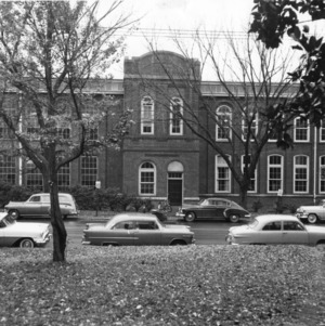Front view of Tompkins Hall, North Carolina State College, showing automobiles parked on Hillsborough Street.