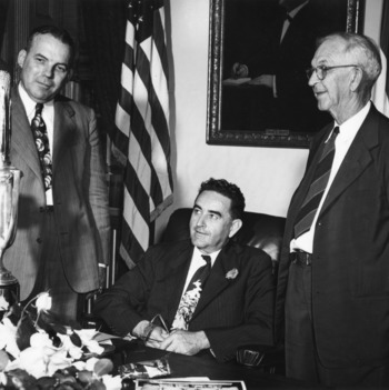Commissioner L. Y. Ballentine, Gov. W. Kerr Scott, and Dean Ira O. Schaub with corn cob-shaped award for winning competition