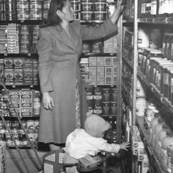 Woman and her child examining goods in the Vetville Mutual Grocery Co-op in the basement of Vetville YMCA.