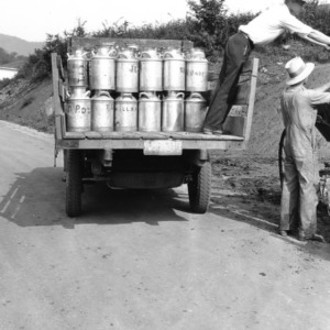 Men loading milk canisters from truck, 1929