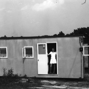 Woman standing in doorway of temporary housing unit, Vetville, North Carolina State College.