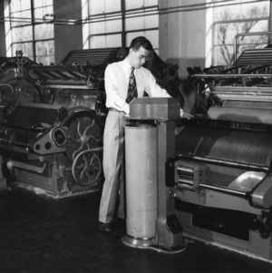 Student operating cotton carding machine at North Carolina State College School of Textiles.