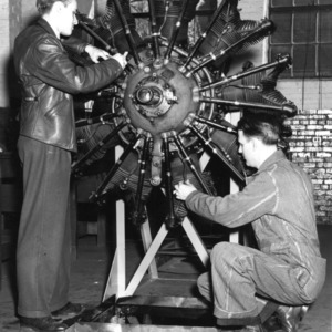 Two men working on airplane engine