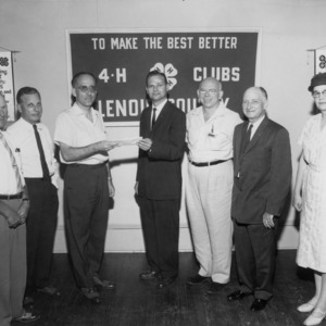 Group of six men and a woman presenting a check for a 4-H fund drive