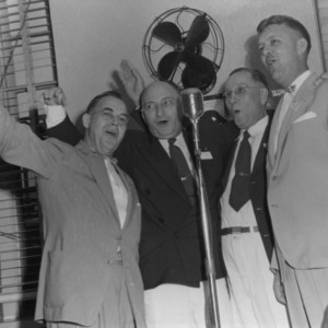 L. R. Harrill and other 4-H leaders singing into microphone