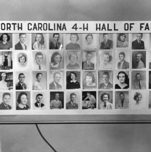 Two North Carolina State 4-H Council officers and an unidentified man stand in front of a display reading "North Carolina 4-H Hall of Fame"