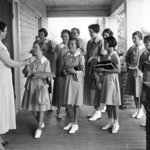 4-H club members holding their notebooks and greeting a woman on a porch