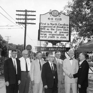 Hertford County 4-H Club leaders and L. R. Harrill in front of historical marker for the formation of the first North Carolina Corn Club in Ahoskie in 1909