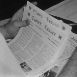 Copies of the 4-H publication Clover Leaves being read by an unidentified man