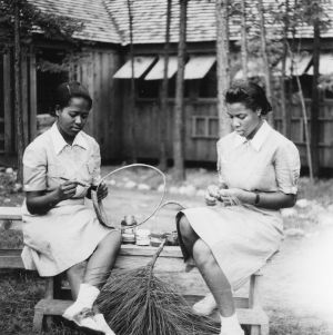 Hattie Baker from Gates County and Sissie Brouche from Warren County demonstrating how to make hot pan mats out of pine needles at the Wake County Whispering Pines 4-H Camp, July 14-17, 1941