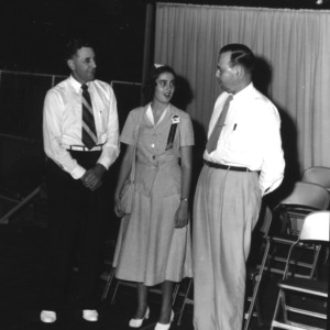 4-H club member speaking with two unidentified men at the 4-H Dress Revue