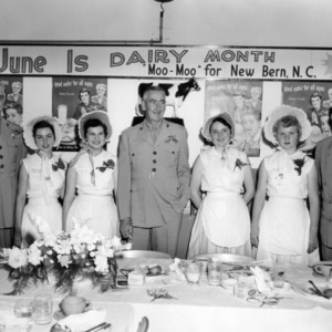 Four 4-H club girls and three unidentified men standing during a dairy foods demonstration in New Bern, North Carolina