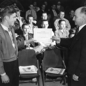 L. R. Harrill presenting a certificate of achievement to a 4-H club member at an awards ceremony