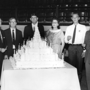 4-H club members and leaders, including L. R. Harrill, standing behind a large cake at the Golden Anniversary