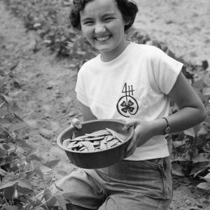 Unidentified 4-H club member displaying her beans grown on the Tew family farm
