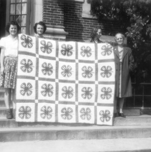 Three 4-H club girls and their leader from Johnston County, North Carolina holding their 4-H quilt