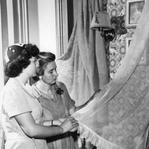 4-H club member and leader examining curtains as part of a 4-H room beautification program