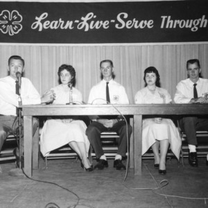 Five 4-H club members sitting onstage at table, speaking into microphones, during North Carolina State 4-H Club Week