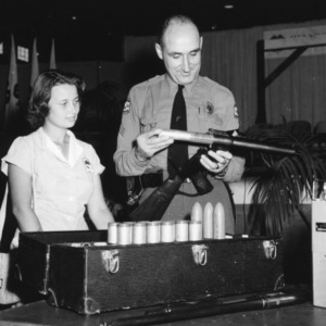 Police officer demonstrating smoke grenade launcher to 4-H club member during North Carolina State 4-H Club Week