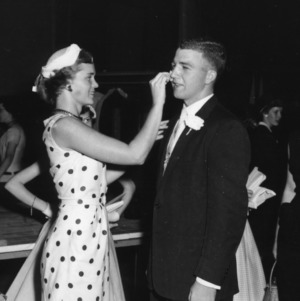 Young woman applying makeup to a young man's face during North Carolina State 4-H Club Week event