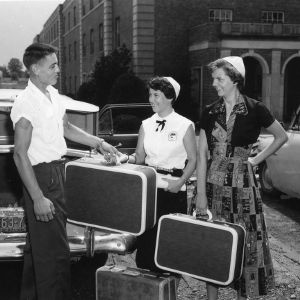 Young man helping two young women with their suitcases