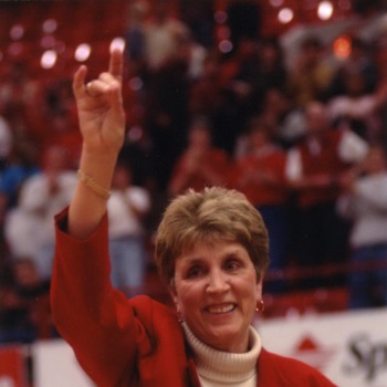 Kay Yow making wolf symbol with her hands at women's basketball game