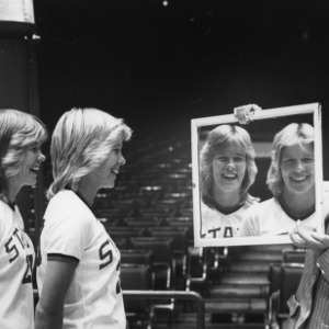 Faye and Kaye Young look at their reflections in mirror held by Head Coach Kay Yow