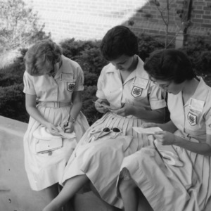 Sarah Jones, Joan Lowman, and Jean Lowman of Burke County writing and reading letters, during 1961 North Carolina State 4-H Club Week