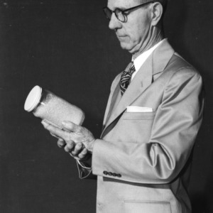 Frank L. Teuton of the United States Department of Agriculture, a speaker at 4-H Club Week, examining a jar of powdered orange juice