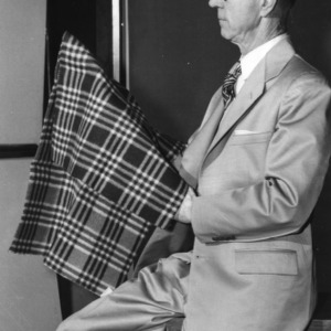 Frank Teuton of the United States Department of Agriculture, a speaker at 4-H Club Week, examining a flame-resistant blanket
