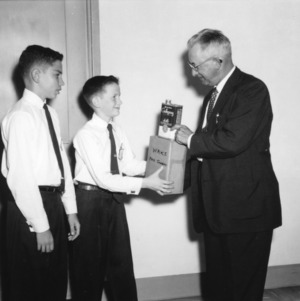 An unidentified man handing a box to two 4-H club members
