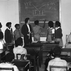Youth participating in the International Farm Youth Exchange (IFYE) program, writing their names on a blackboard