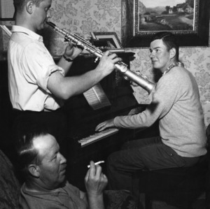 Two unidentified 4-H club members playing instruments -- the piano and the soprano saxophone -- while an unidentified man smokes