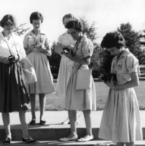 Four Cabarrus County girls examining their cameras as part of a 4-H photo club
