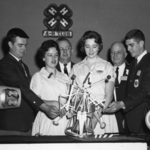 4-H club members examining model of a satellite. L. R. Harrill, second from right