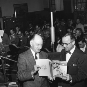 L. R. Harrill (left), North Carolina State 4-H Club leader and Howard Todd (right) of American Oil Company, sponsor of the Tractor Maintenance School for 4-H adult leaders, reading a book on the 4-H tractor program