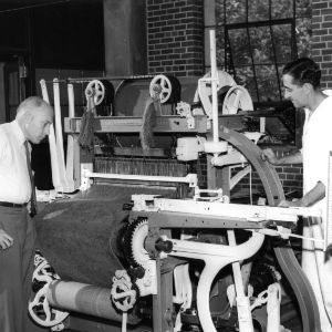 Professor Whittier (left) inspects a carpet loom by Bigelow Sanford, N.C.
