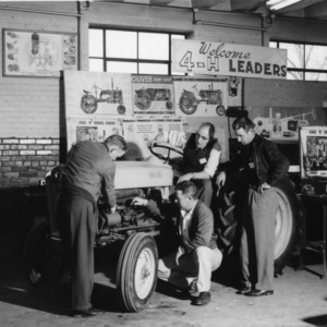 J. C. Ferguson, seated, and three leaders discuss timing [at a 4-H Club tractor program]