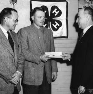 L. R. Harrill, right, State 4-H Club Leader, presents Gene Cornwell of Route, 1, Shelby, Cleveland County, the certificate of Participation in the Tractor Leaders' Training School as H. F. Todd, left, Manager, Farm Dept., American Oil Company, looks on